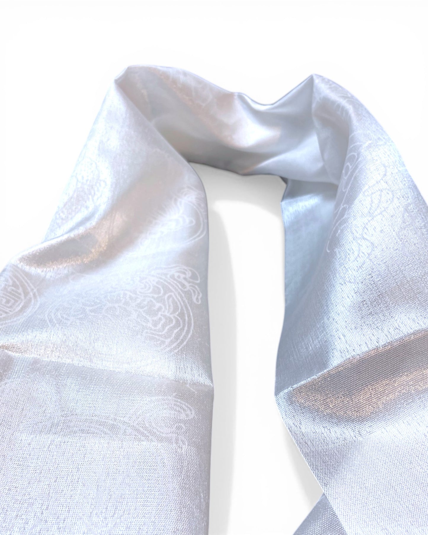 Detailaufnahme eines weißen Khatag Schals mit seidigem Glanz und eingewebten tibetischen Symbolen.