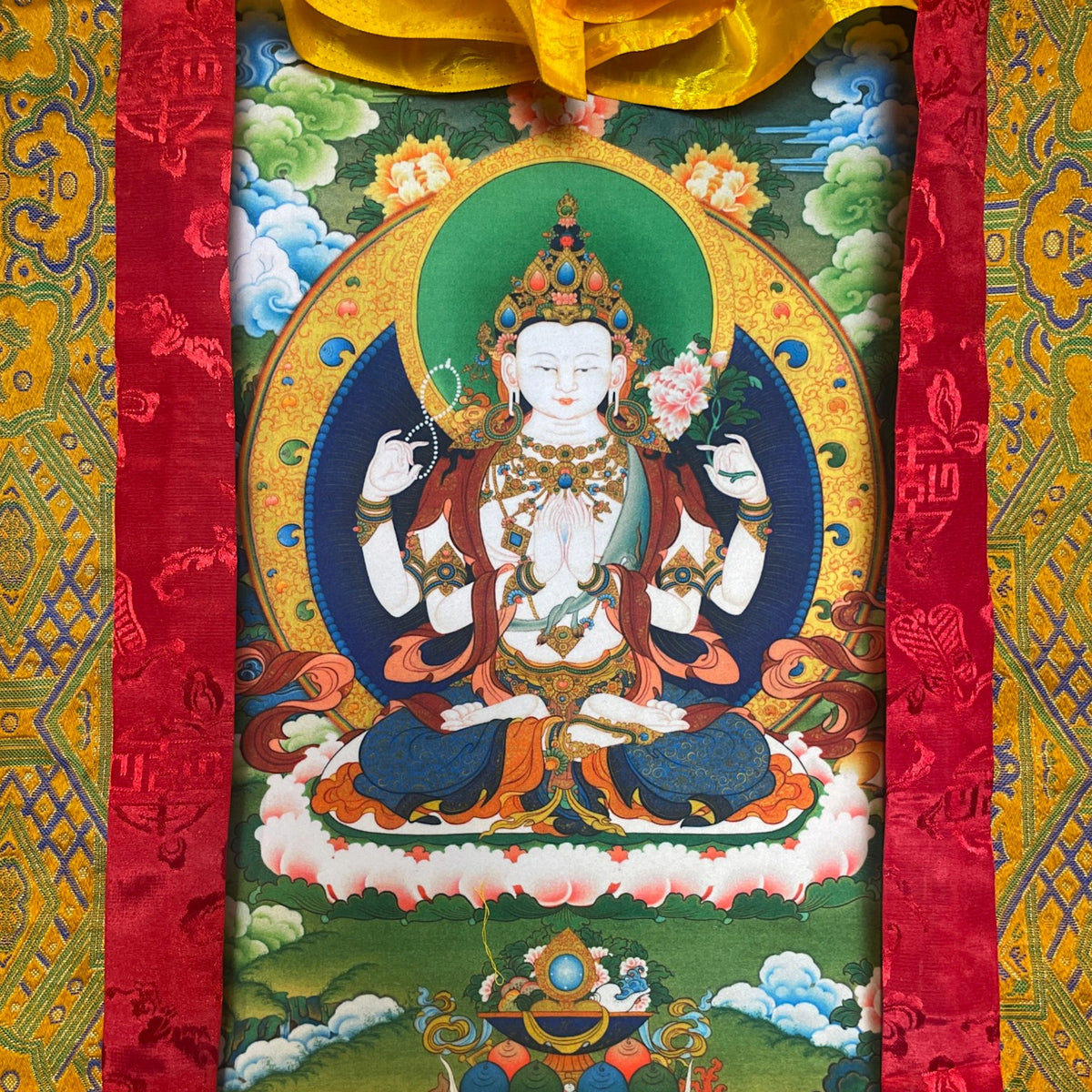 Gros plan du motif de Chenrezig sur le thangka, à quatre bras sur un trône de lotus