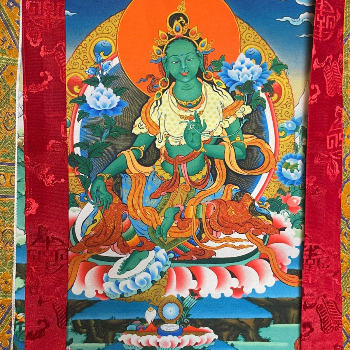 Tara verte sur un trône de lotus devant un disque solaire orange avec pivoines bleues, gros plan du motif du thangka
