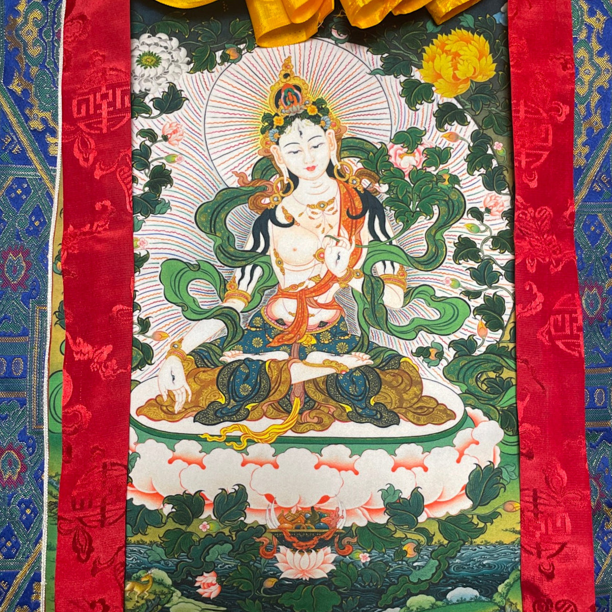 Primo piano della Tara bianca sul thangka con alone di raggi e peonie