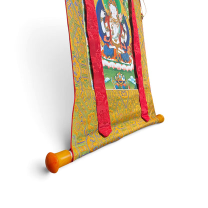 Détail de la barre aux extrémités orange et du brocart, thangka Chenrezig – Himalaya Vibes