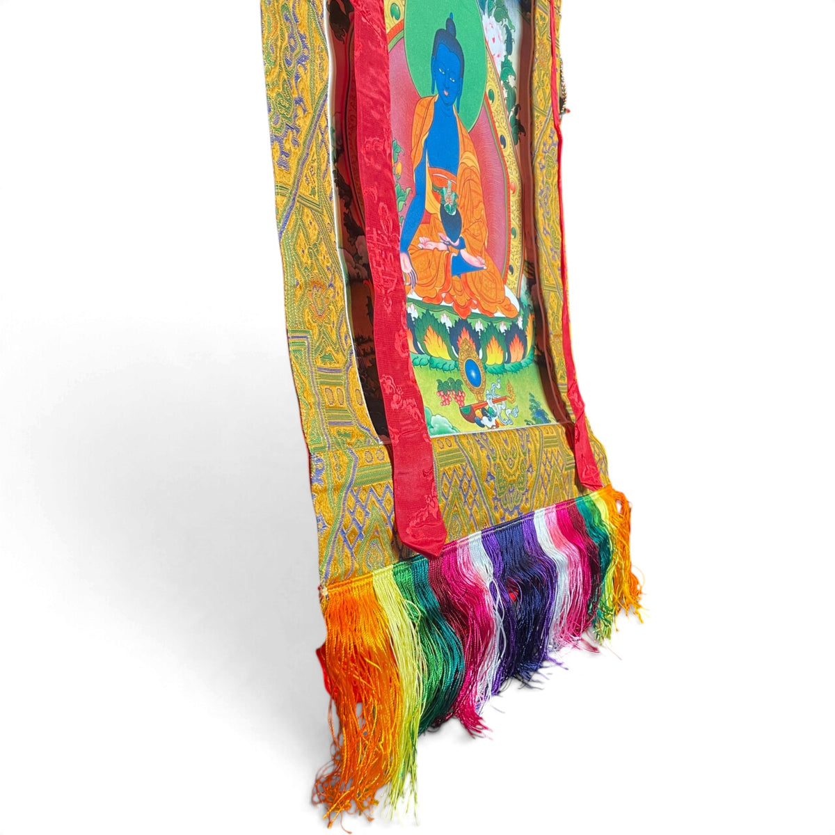 Dettaglio delle frange di seta colorate e della cornice in broccato del thangka Buddha della Medicina