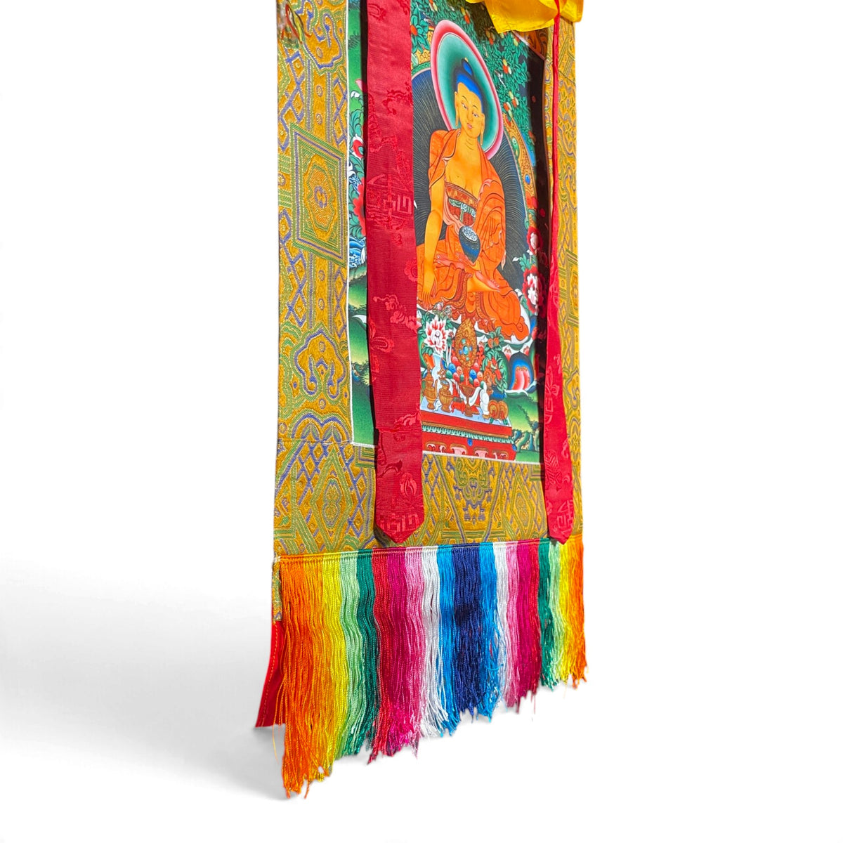 Détail des franges de soie multicolores et du cadre en brocart du thangka Shakyamuni