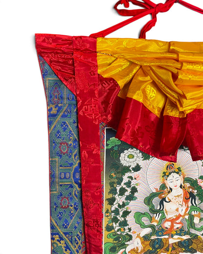 Detail oben: gelbe Seidenschürze, rote Seidenbänder und Aufhängeschnur am Weisse Tara Thangka