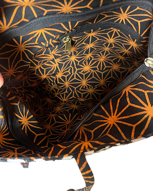 Innenansicht der Boho Stofftasche mit schwarzem Innenfutter und orangefarbenem geometrischem Muster sowie Reissverschlussfach.