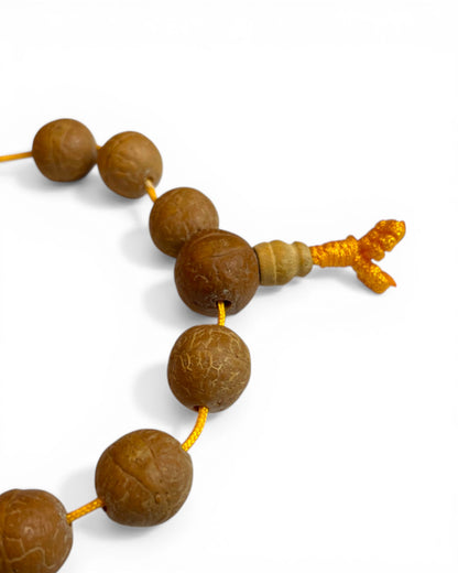 Detailansicht der Bodhi Samen Perlen und des gelben Verschlussknotens des Mala Armbands.