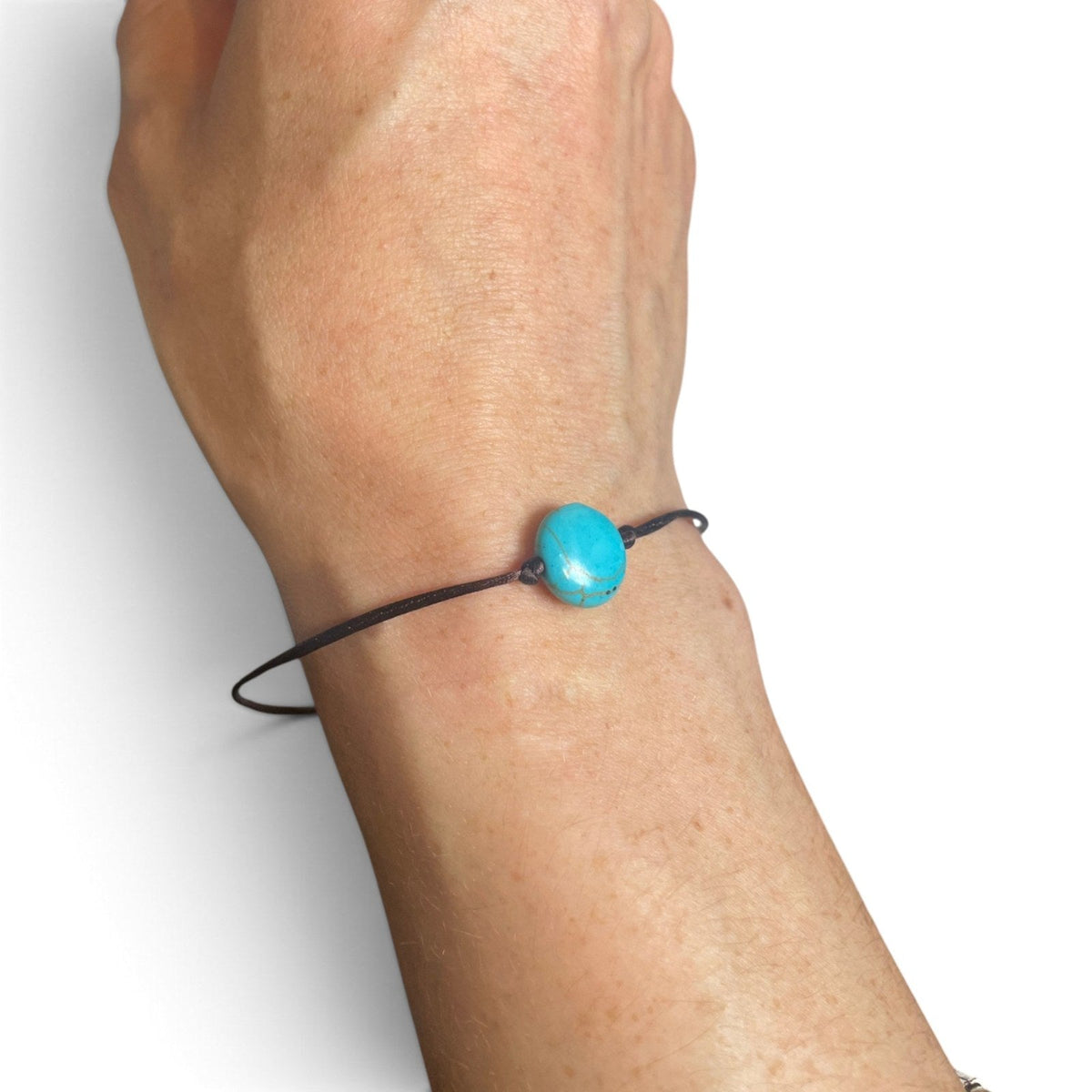 Bracelet porte-bonheur brun avec perle bleu turquoise porté au poignet