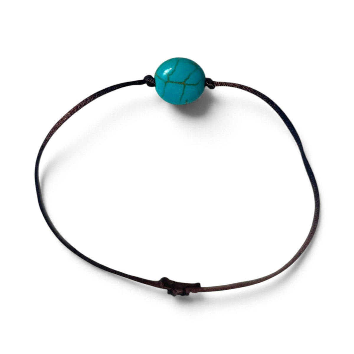 Bracelet noué brun avec perle bleu turquoise posé à plat