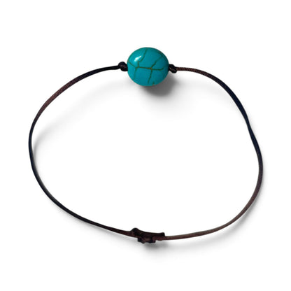 Bracelet noué brun avec perle bleu turquoise posé à plat