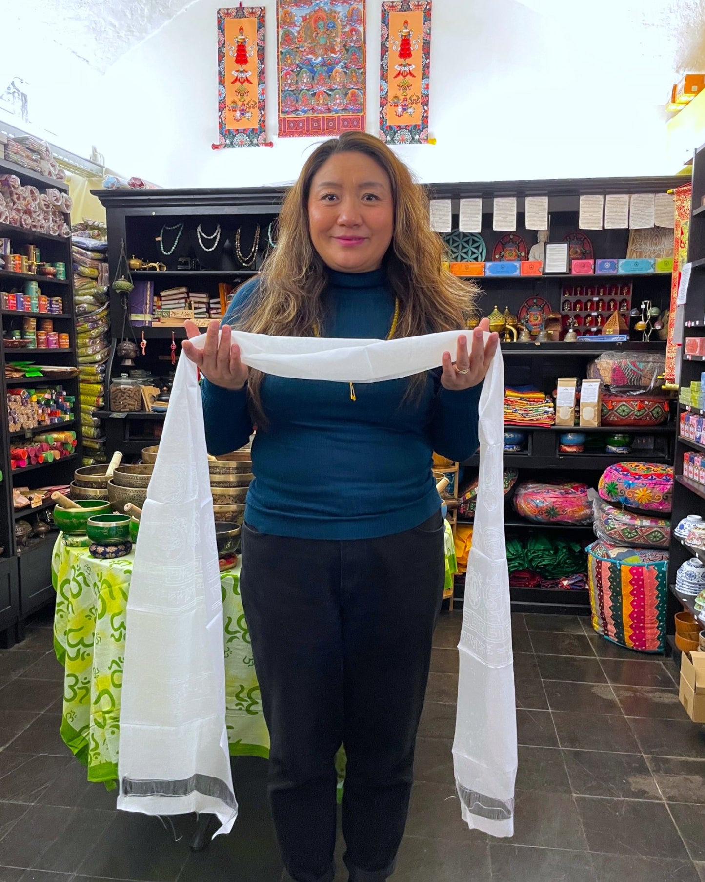Inhaber von Himalaya Vibes Bern hält einen weißen tibetischen Khata Schal in ihrem Laden.