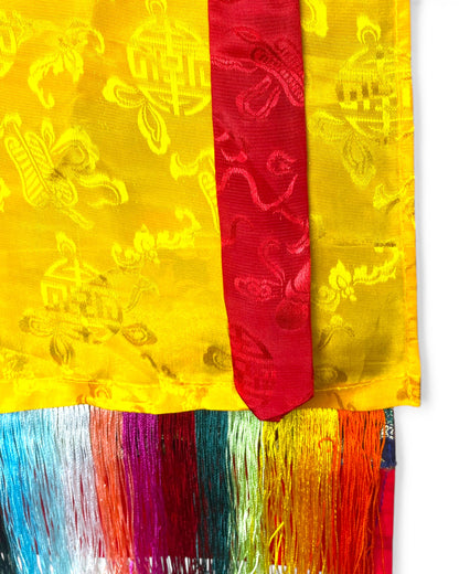 Detailansicht der gelben Seide und der roten Baender des Thangka-Schutzvorhangs.