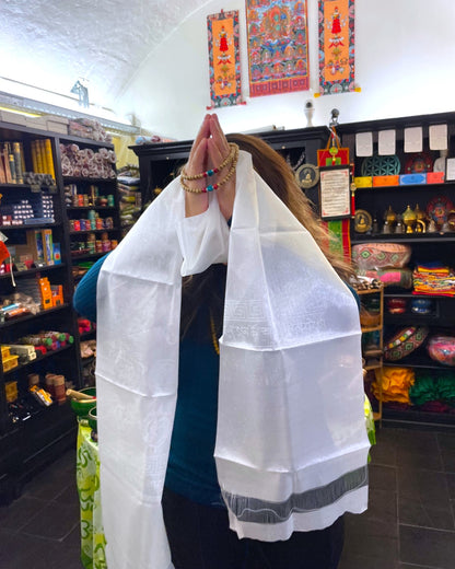 Respektvolle Geste: Frau hält den Khata Schal mit gefalteten Händen vor das Gesicht, Mala Perlen sichtbar.