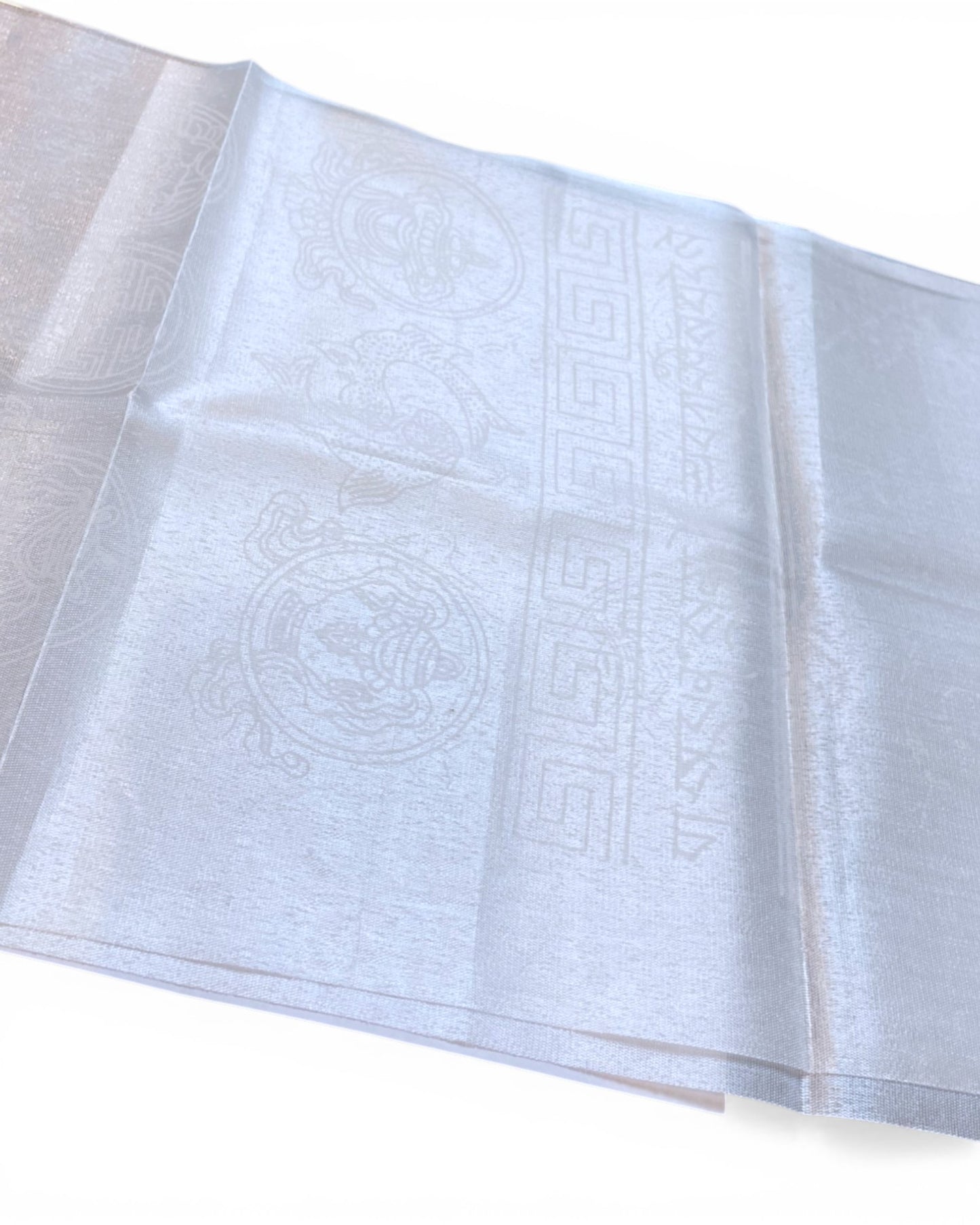 Nahaufnahme eines weißen Khatag Schals mit detaillierten tibetischen Glückssymbolen und Schriftzeichen.