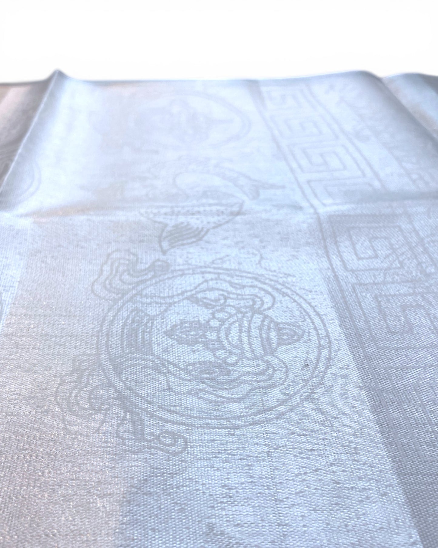 Makroaufnahme der Webstruktur und des feinen Glanzes eines weißen Khata Begrüßungsschals.