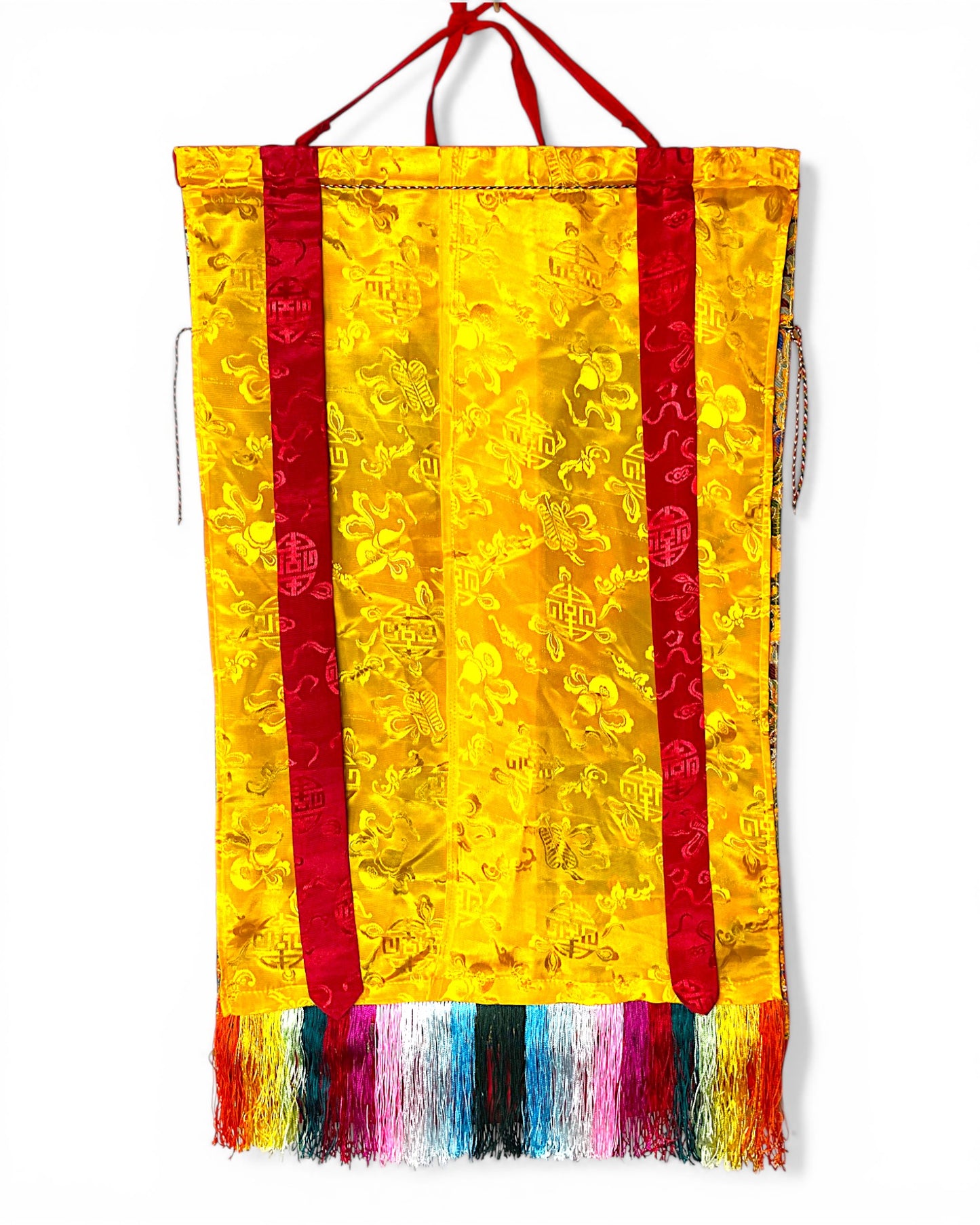 Rückseite des Medizin-Buddha Thangkas aus gelber Seide mit traditionellen Mustern.
