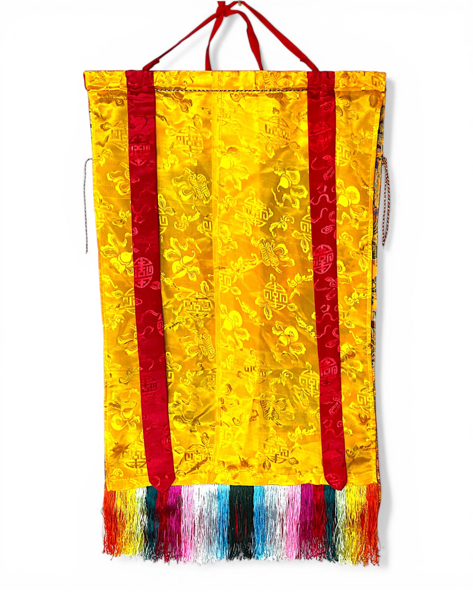 Rückseite des Medizin-Buddha Thangkas aus gelber Seide mit traditionellen Mustern.
