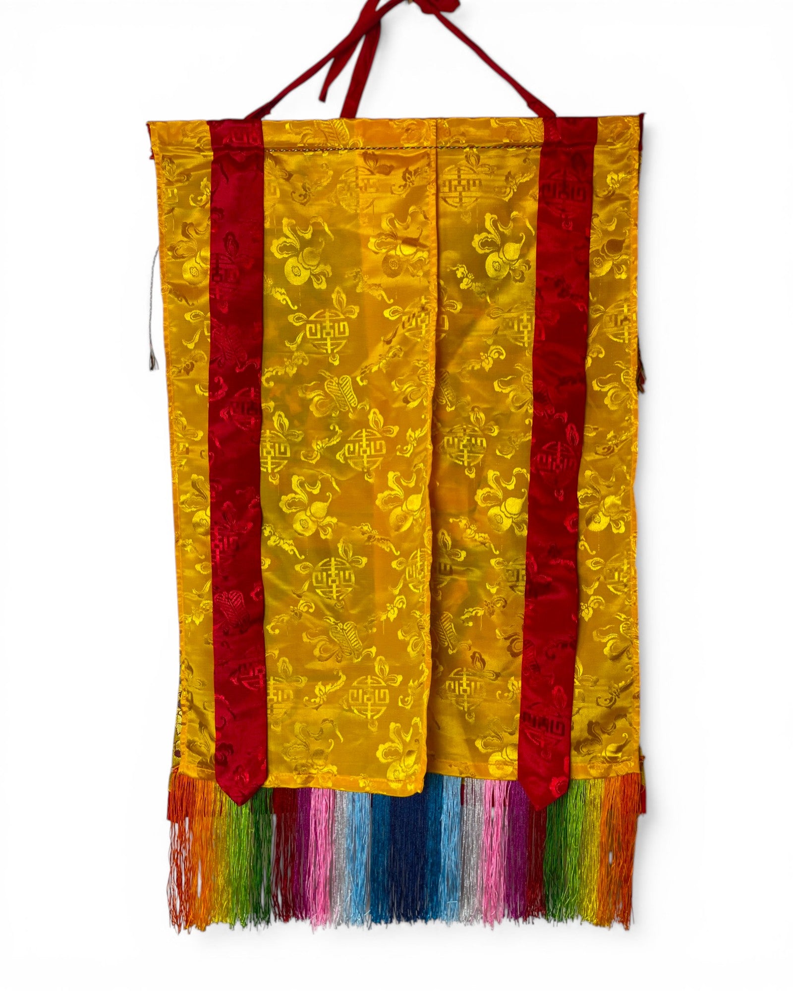 Vorderseite des Thangkas mit schützender gelber Seidenabdeckung und traditionellen Mustern.