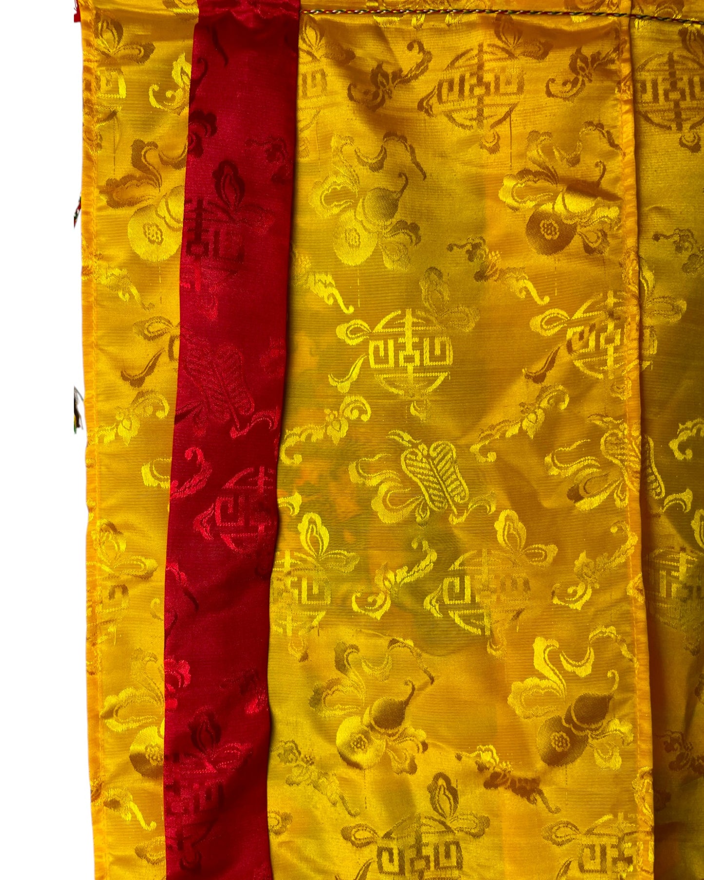 Makroaufnahme des gelben Seidenstoffs mit eingewebten Glückssymbolen für den Online-Shop.