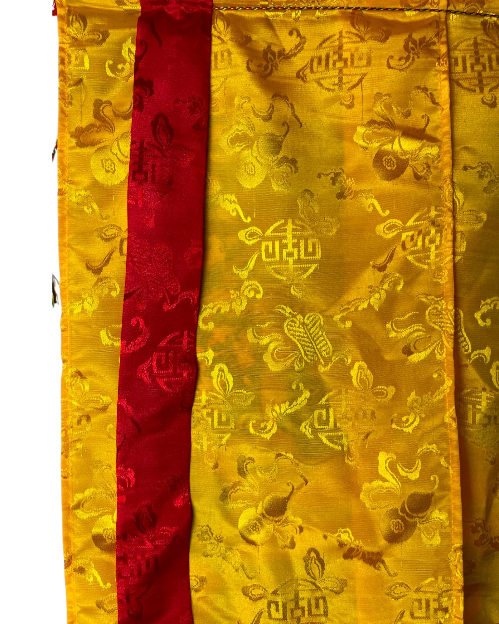 Makroaufnahme des gelben Seidenstoffs mit eingewebten Glückssymbolen für den Online-Shop.