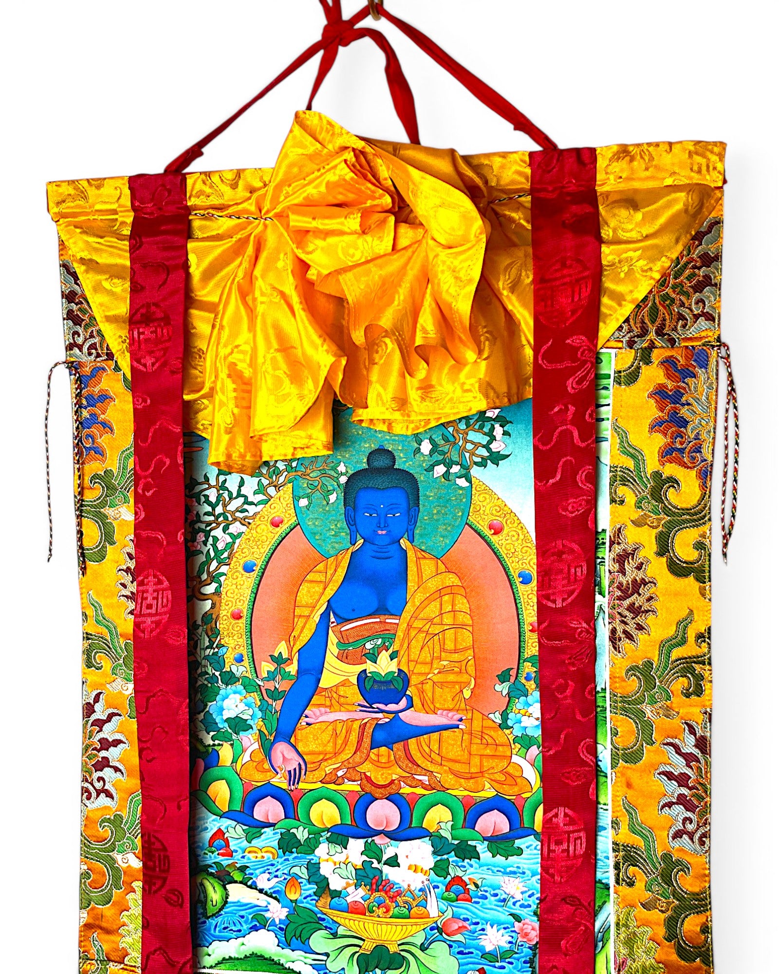 Detailansicht des tibetischen Medizin-Buddha Thangkas mit gelber Seidenabdeckung.